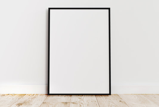 Blank vertical black poster frame standing on light wooden floor with next to white wall. Blank poster frame mockup. Empty picture frame mockup. Vertical frame mock up. Blank photo frame. 3d rendering