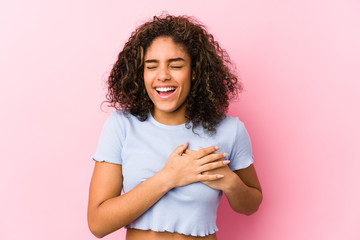Young african american woman against a pink background laughing keeping hands on heart, concept of...