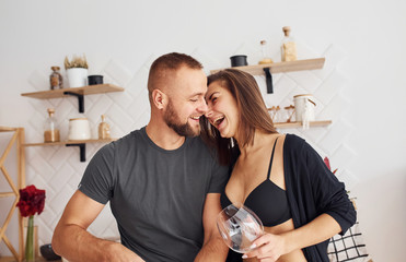 Woman in sexy black lingerie with her husband on the kitchen