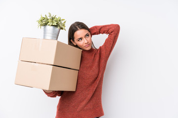 Young caucasic woman holding boxes isolated touching back of head, thinking and making a choice.