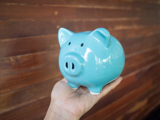 A hand holding a blue piggy bank. To encourage for saving money