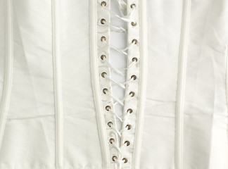 fragment of a white satin corset with lacing