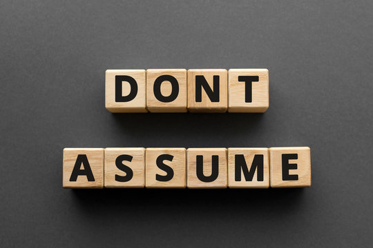 Don't assume - words from wooden blocks with letters, don't assume concept, top view gray background