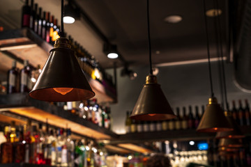 Vintage dark lamps hanging on the ceiling of a restaurant bar on a dark background.