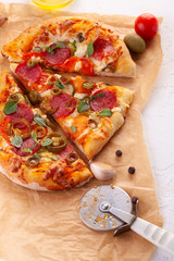 Homemade spicy pepperoni pizza and cooking ingredients. Pepperoni pizza on a white wooden table.
