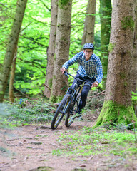 Fototapeta na wymiar Verwegene Mountainbiker beim Downhill auf Wald-Trails