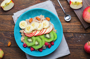 Spelt Porridge with Fruits in a Bowl over Wooden Background