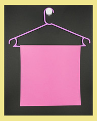 Plastic purple hanger with a lilac sheet of paper on a dark background.