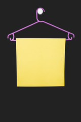 Plastic purple hanger with a yellow sheet of paper on a dark background.