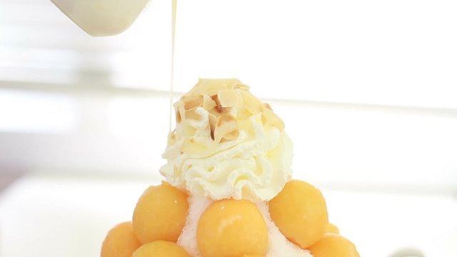 Puring Sweetened condensed milk on Shaved ice in melon fruit. Healthy eating with Diet and sweet food concept.