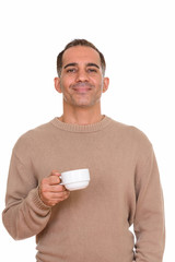 Mature happy Persian man holding coffee cup