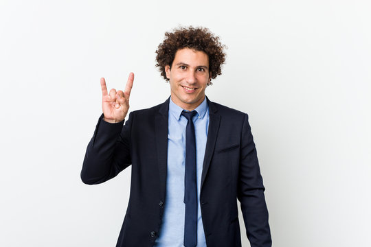 Young business curly man against white background showing a horns gesture as a revolution concept.