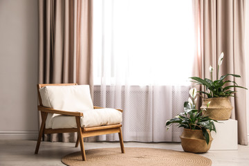 Comfortable armchair near window with elegant curtains in room