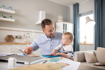 Bearded man in a blue shirt holding his kid and smiling