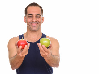 Mature happy Persian man holding red and green apple