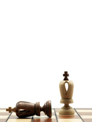 Obraz na płótnie Canvas Defeated Black King Chess Piece Lying Next To A Standing White King, Chess Board With White Background