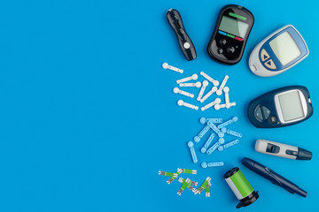 Glucometer. A device for measuring blood sugar levels. Test strips, pills on a blue background.