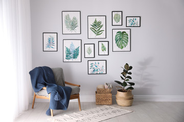 Beautiful paintings of tropical leaves on white wall in living room interior - Powered by Adobe
