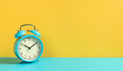 Alarm clock on turquoise yellow background. Front view.