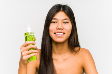 Young chinese woman holding a moisturizer with aloe vera isolated happy, smiling and cheerful.