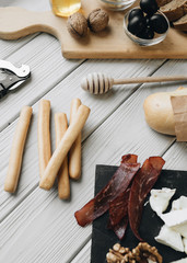 Flat lay with assorted food, glass for wine and nuts on light surface 