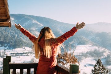 Woman standing with her hands raised facing the mountains in winter time