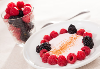 breakfast of raspberries and blackberries with yogurt on table
