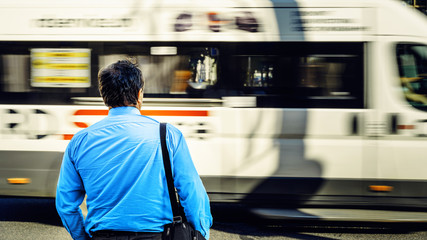 A man in a blue shirt in the bustle of the city against the backdrop of a passing bus. Man near the...