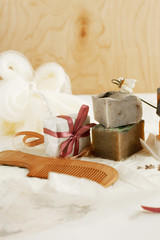 Beautifully packaged natural handmade soap in paper and colored ribbons, natural loofah and wooden hair comb with cloves on a decorative background. Natural care concept. Selective focus