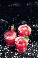 Summer cocktail with watermelon on black metal surface.