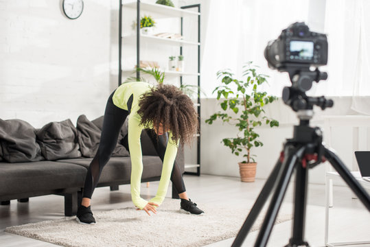 selective focus of sportive african american video blogger exercising near digital camera - Powered by Adobe