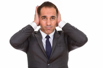 Stressed mature Persian businessman in suit covering ears