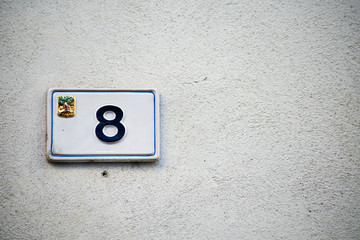 Italian house number ceramic plate sign mounted on the wall. With number 8 (eight).