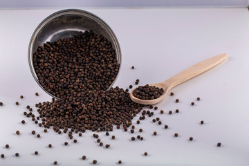 black pepper in wooden spoon isolated on white