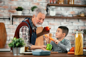 Grandpa and grandson in kitchen. Grandfather and his grandchild having fun while cooking. 