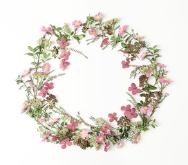 Beautiful and tender wreath frame with pink flowers, branches, leaves and petals on white background. Flat lay style. Overhead view. Copy space.