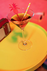 Cocktail beverage and vintage radio on yellow table next to sunbed.