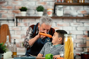 Grandpa and grandson in kitchen. Grandfather and his grandchild having fun while cooking. 