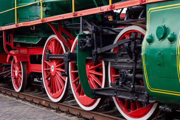 Old black and red retro steam locomotive wheels at the railway station. Vintage train staying on the railroad