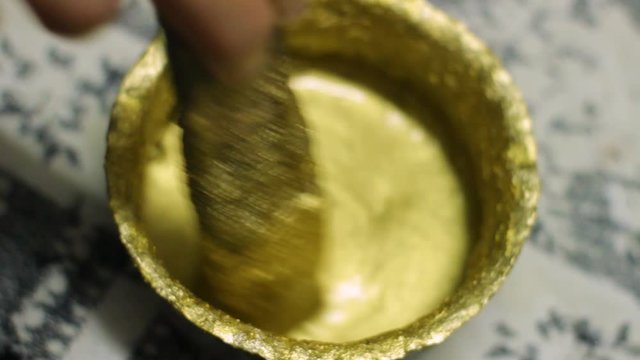 hand stirring fresh golden paint 