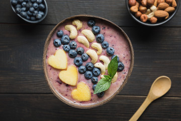 Healthy breakfast banana and blueberry smoothie decorated with fruits in coconut bowl.