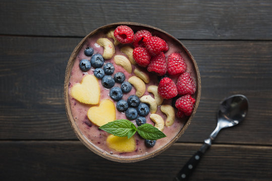 Healthy Breakfast Banana And Blueberry Smoothie Decorated With Fruits In Coconut Bowl On Wooden Board. View From Above. Clean Eating, Vegetarian Food Concept.