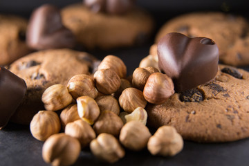 Hazelnuts near a chocolate heart and cookies with cocoa