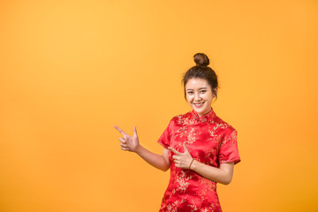 Asian woman smile in Chinese dress presenting free space yellow background. Chinese new year festival.