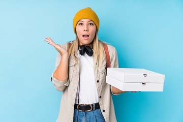 Young caucasian woman holding pizzas isolated surprised and shocked.