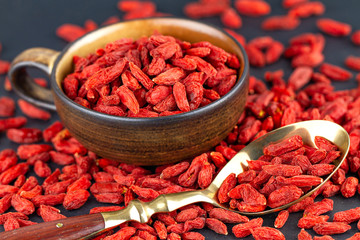 Goji berries in cup with vintage spoon on gray slate. View from above, selective focus