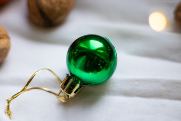  One green christmas ball lies on a light background. Christmas atmosphere.