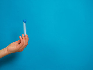 Hand with analysis tube on blue background with copy space