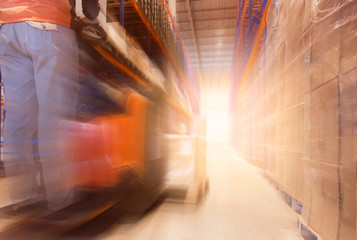 Fototapeta premium Fast motion blur of forklift driver loading pallet in storage warehouse