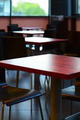 interior design with red tables and wooden chairs, against the background of windows with daylight, selective focus